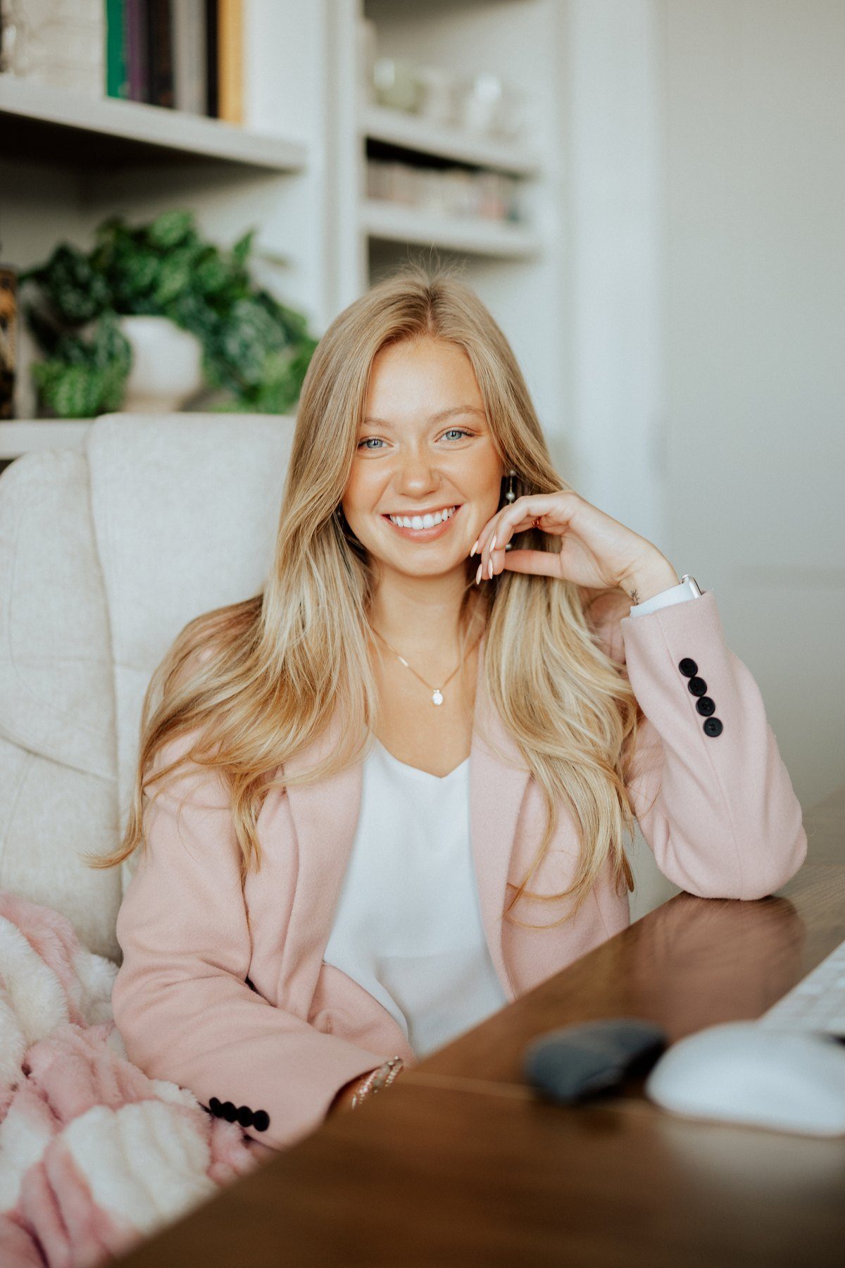 Sabra, interior designer and owner of Sabra & Co., seated at her desk in a pink blazer